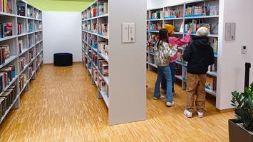 Drei Personen vor einem Bücherregal in einer Bibliothek