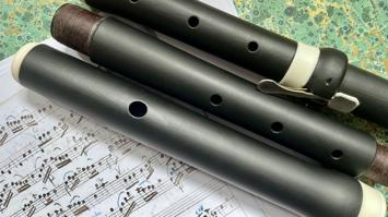 Drei Teile einer (auseinandergebauten) Traversflöte auf handschriftlichen Noten