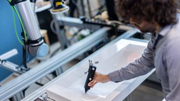 Mitarbeiter:in arbeitet gemeinsam mit einem Cobot