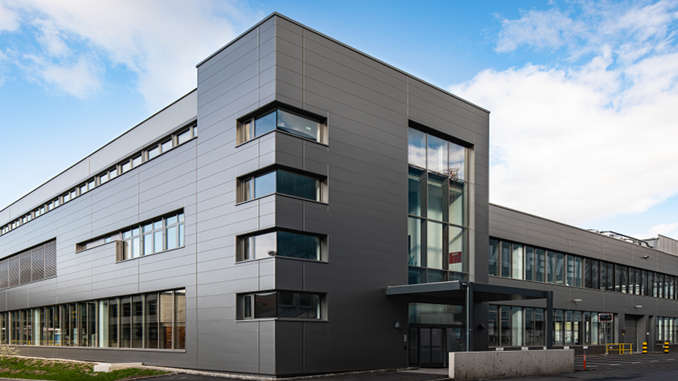 Zweistöckiges, modernes, graues Gebäude mit Glasfronten.