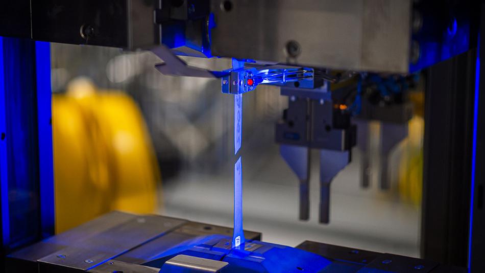 Nahaufnahme einer Stahlprobe während des Zugversuchs unter blauem Licht.