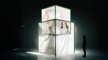 Schatten von Menschen in beleuchtetem milchglasweißem Kubus