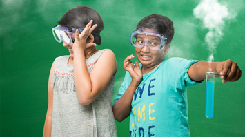 Zwei Kinder experimentieren mit einem Reagenzglas, aus dem Rauch aufsteigt